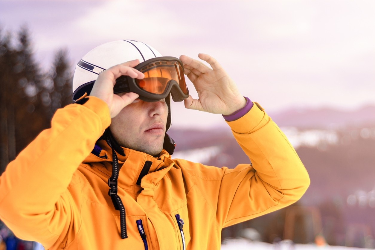 Man wearing orange ski goggles and white helmet