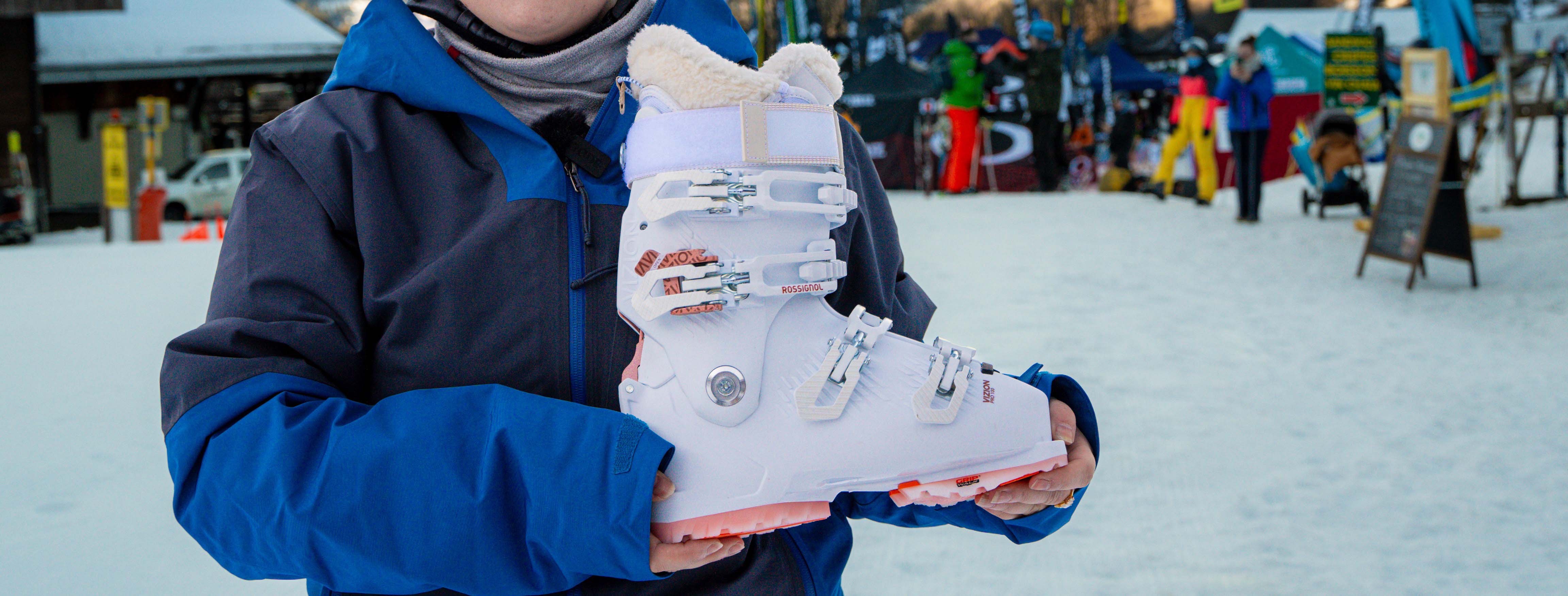 A woman in a blue Patagonia ski jacket holding the Rossignol Women's Vizion Ski Boot