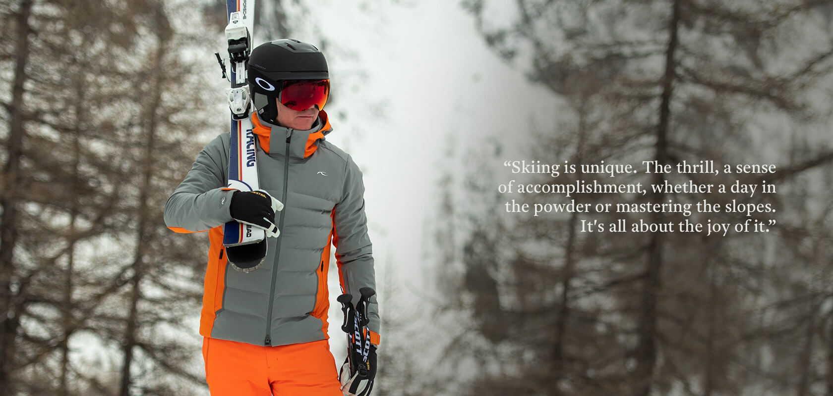 Person dressed in ski gear walking holding poles and carrying skis on his shoulder