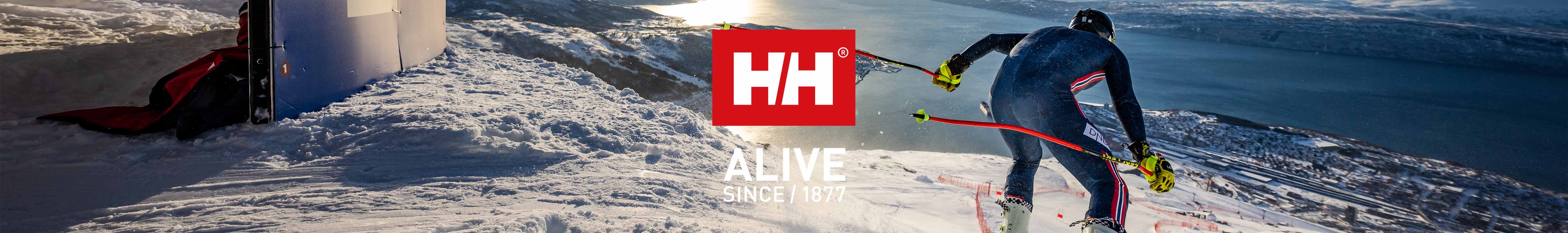 Helly Hansen brand page header image. A man skiing downhill wearing Helly Hansen ski wear