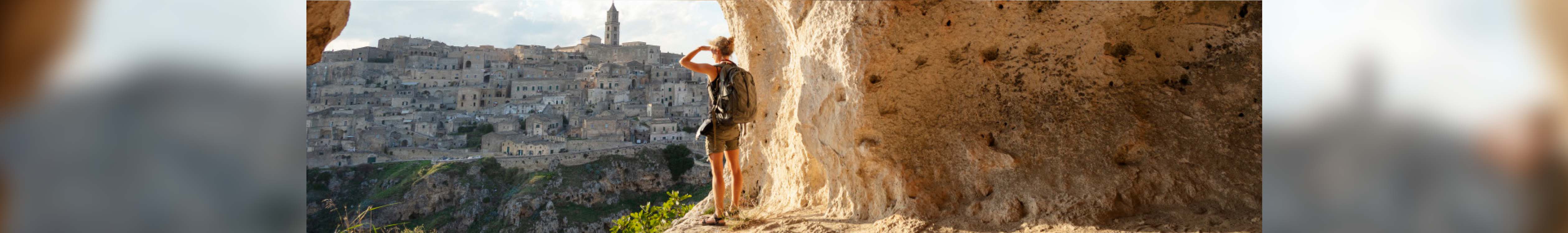 City break. A woman standing on the side of a mountain looking at the town across the valley