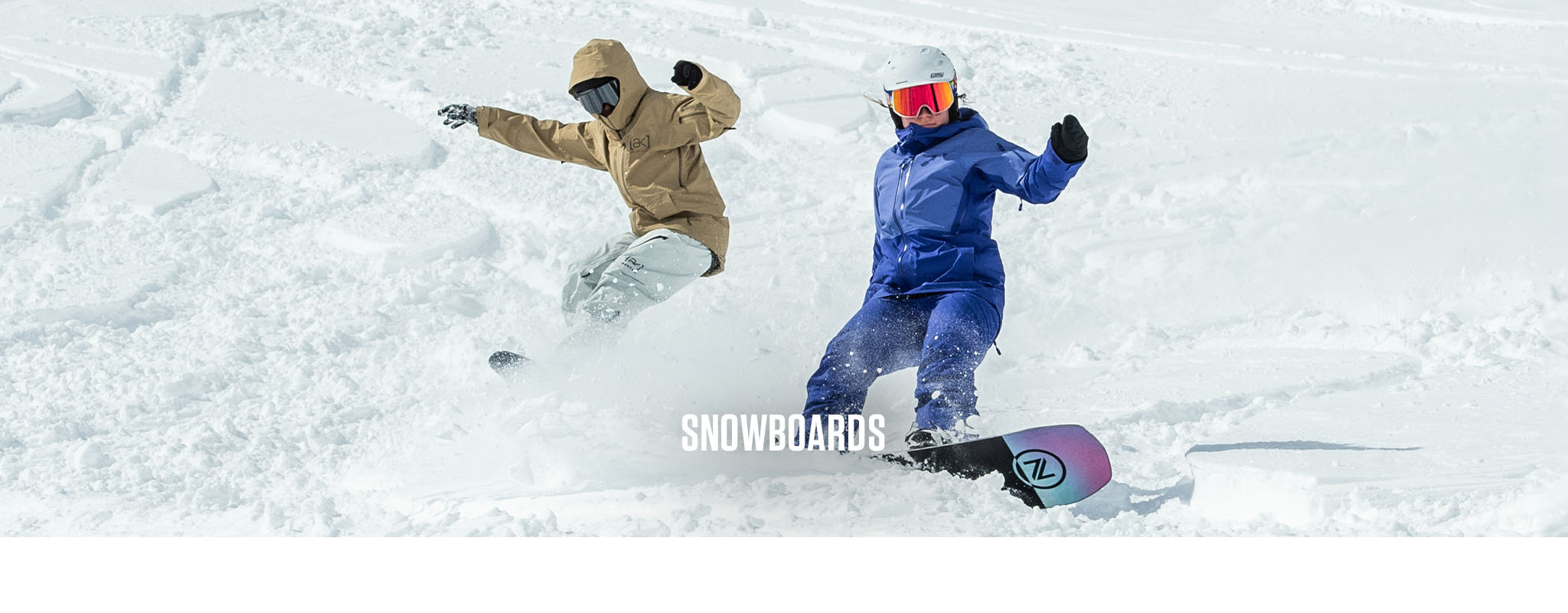 Shop Snowboards. Two people snowboarding down a snowy mountain