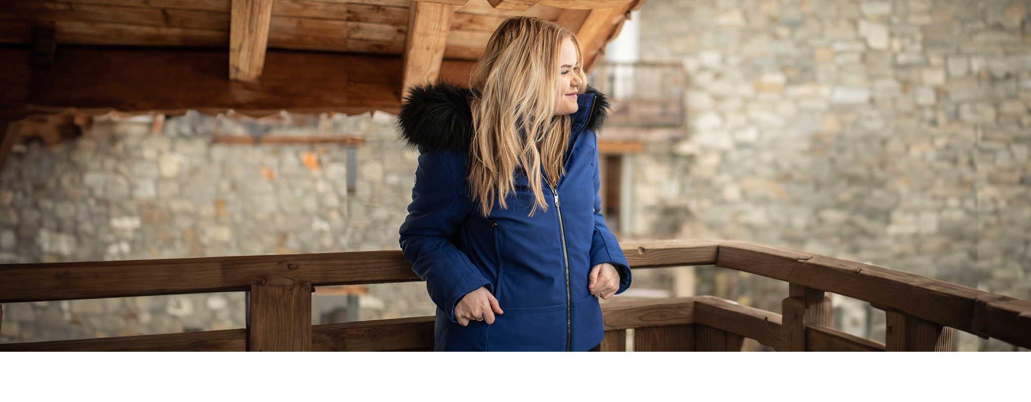 Shop luxury gifts. A woman in a chalet wearing a luxurious ski jacket 