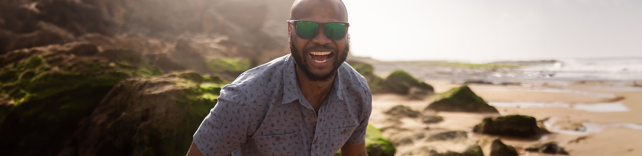 Men's new season. A man is smiling in a grey summer short by the beach 