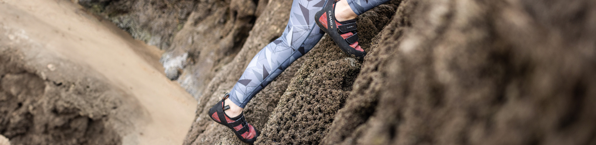 Shop climbing shoes. A person is climbing a rock, wearing climbing shoes