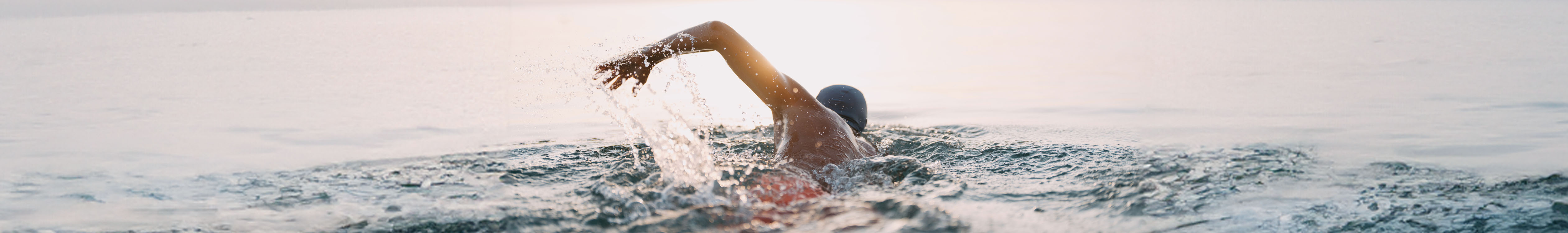 Shop Men's swimwear. A man swimming in a sea.