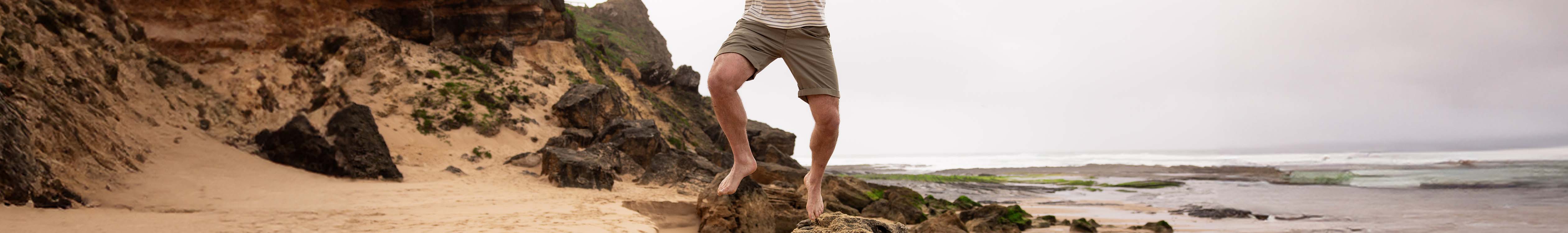 Shop shorts. A man jumping on a beach