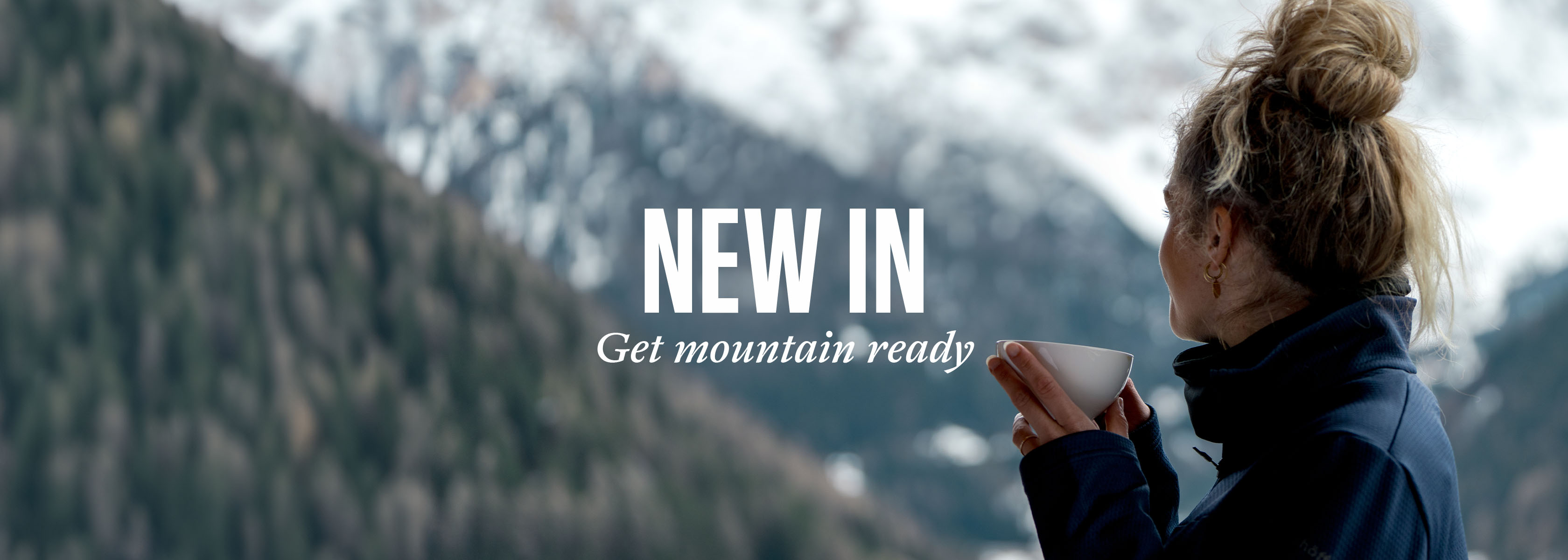 Shop new arrivals. Woman holding a drink mug with snowy mountains in the background