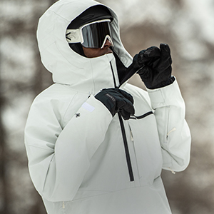 Shop Ski Accessories. A person in white jacket wearing black gloves standing in a snow