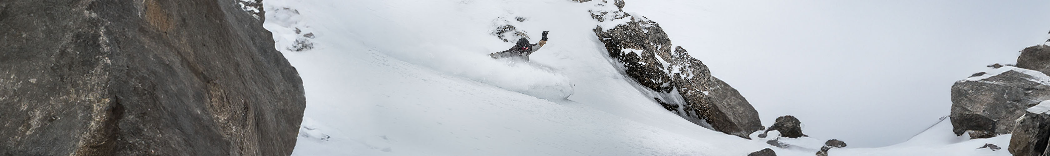 Shop off piste safety. A person snowboarding in deep snow