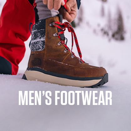 Shop men's footwear. A man is tieing up his snowboots