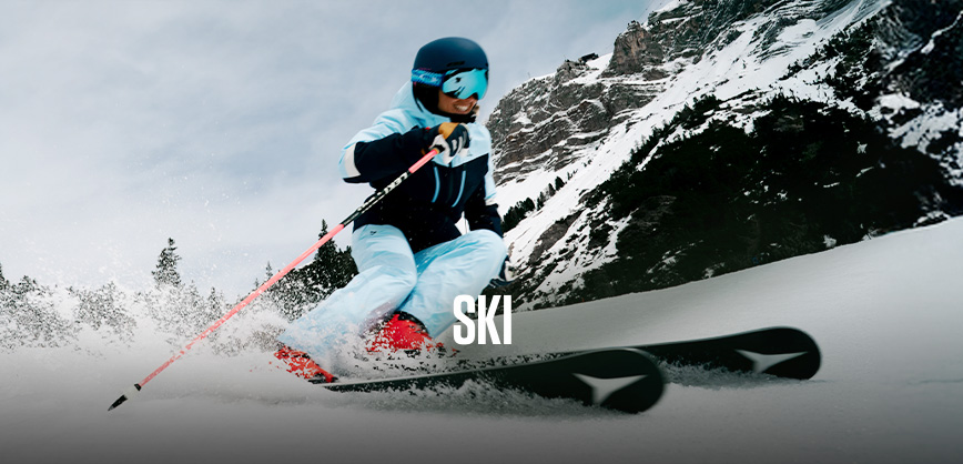 Shop ski new season. A person in blue ski gear skiing down the mountain