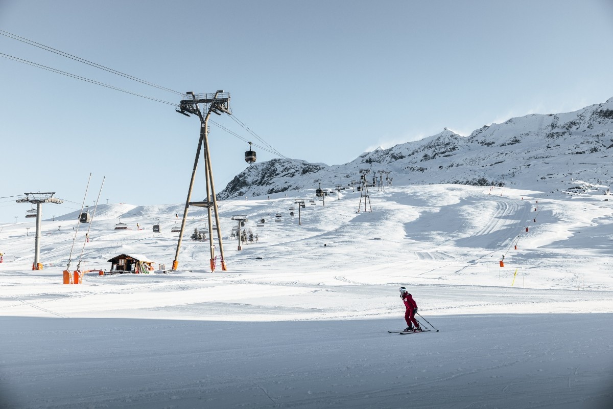 A chair lift with a person skiing below at Alpe d'Heuz ski resort