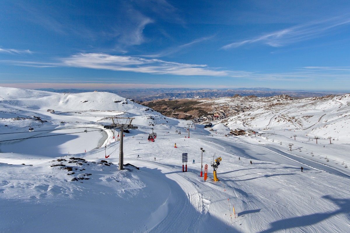 A snowy piste with lots of ski enthusiasts skiing in Sierra Nevada Ski Resort