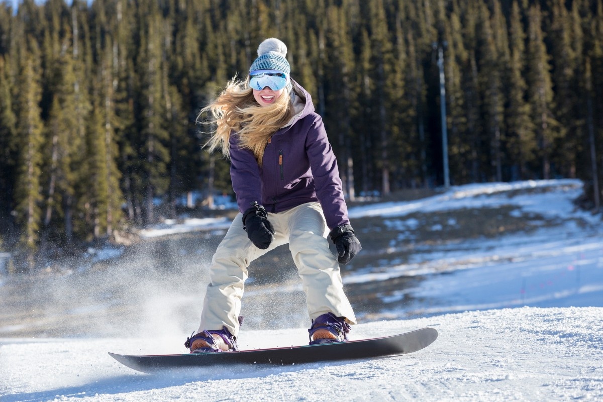 A woman snowboarding wearing salopettes