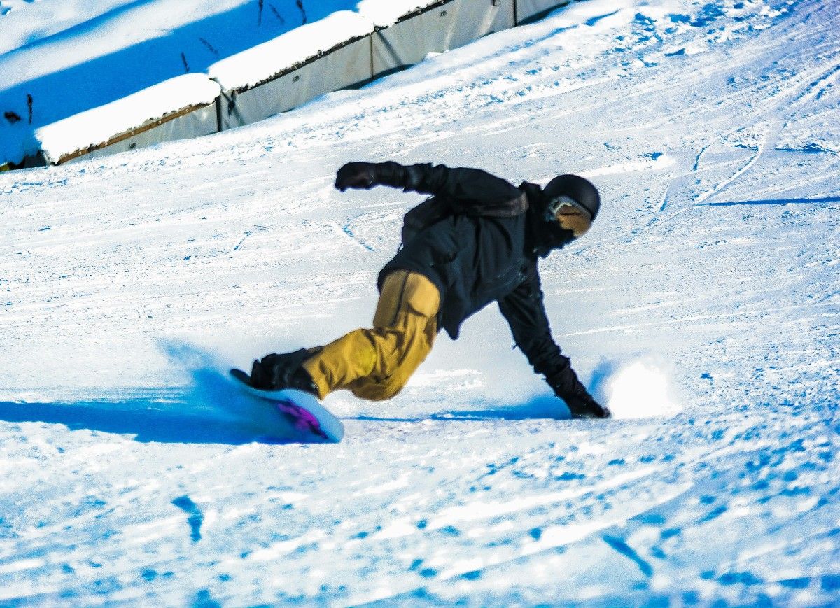 A person snowboarding, touching the snow with his ski gloves 