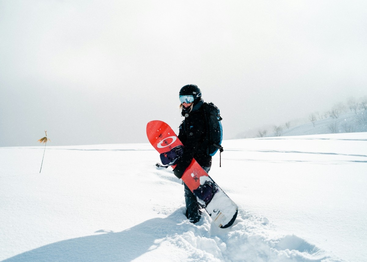 A snowboarder holding his snowboard in the snow 