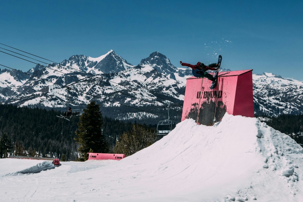 A person performing a snowboarding stunt wearing a snowboarding jacket 