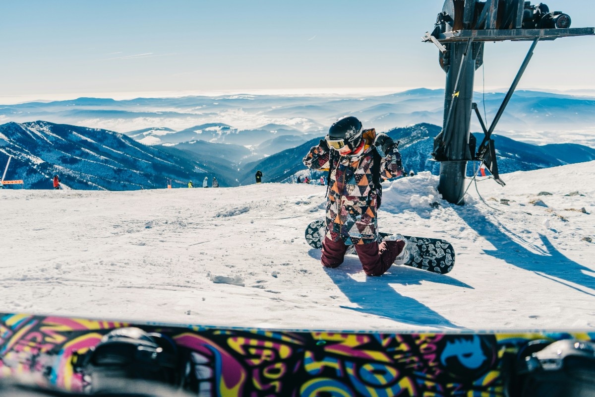 A person snowboarding in a patterned snowboarding jacket 