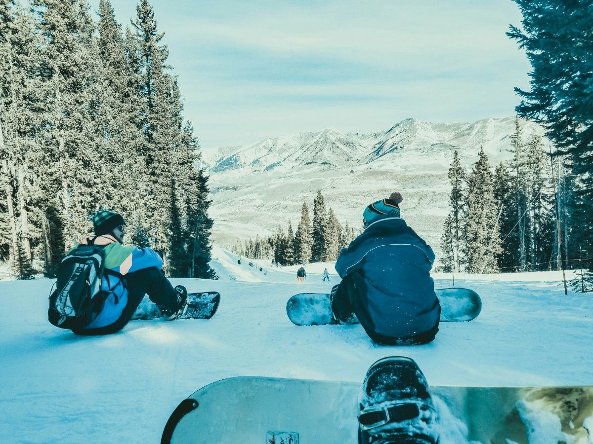 Three snowboarders sat having a rest on the mountain