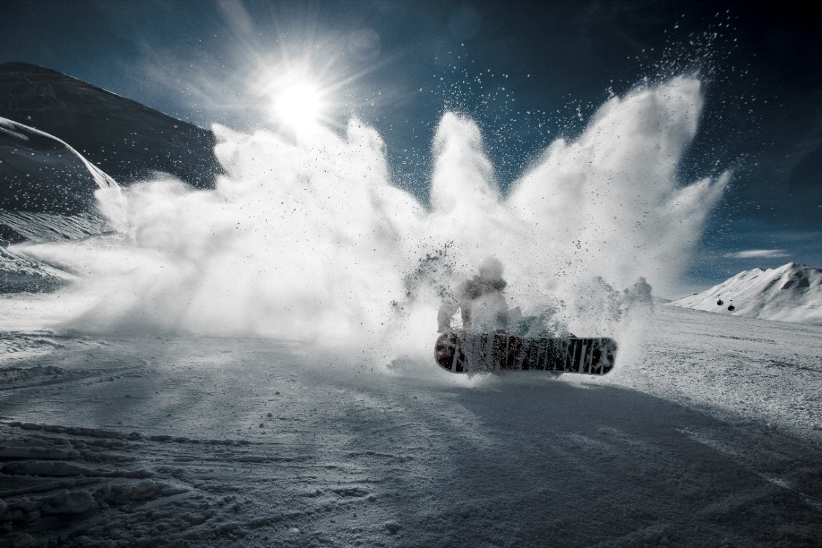 A snowboarder creating a snow shower with their board 