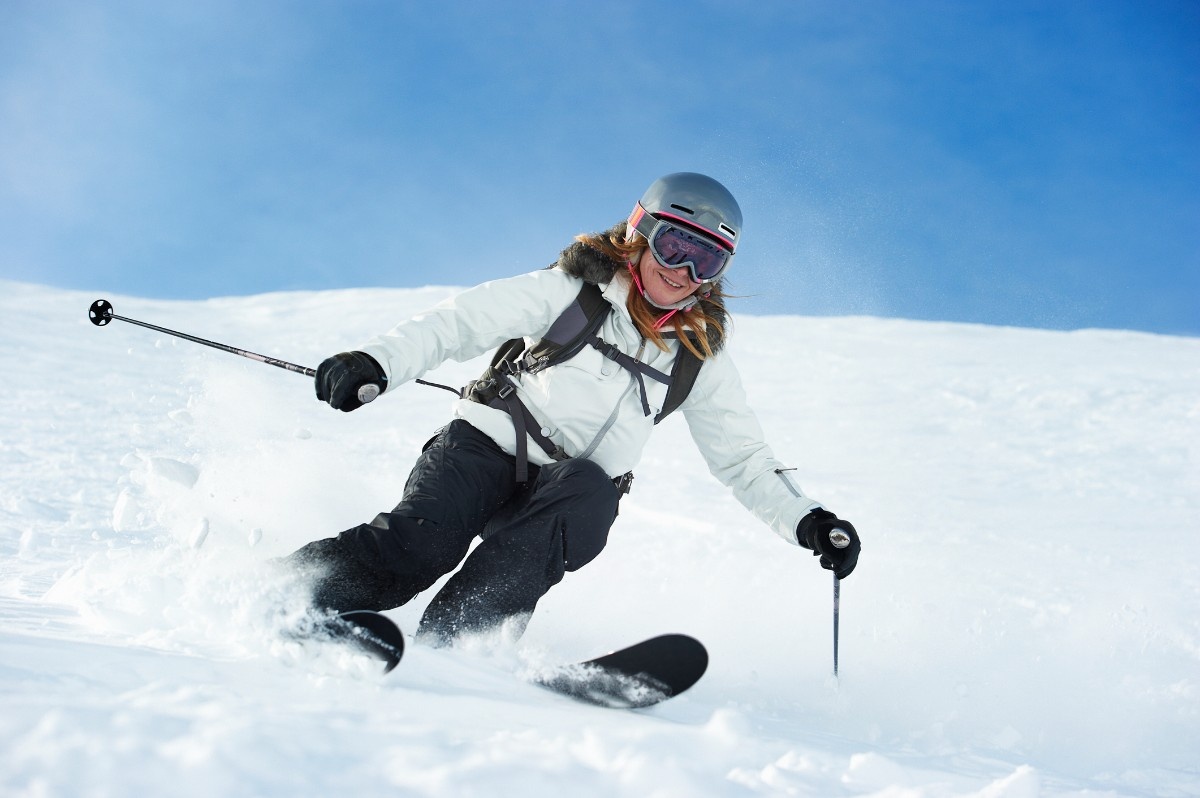 A woman skiing wearing a white ski jacket 