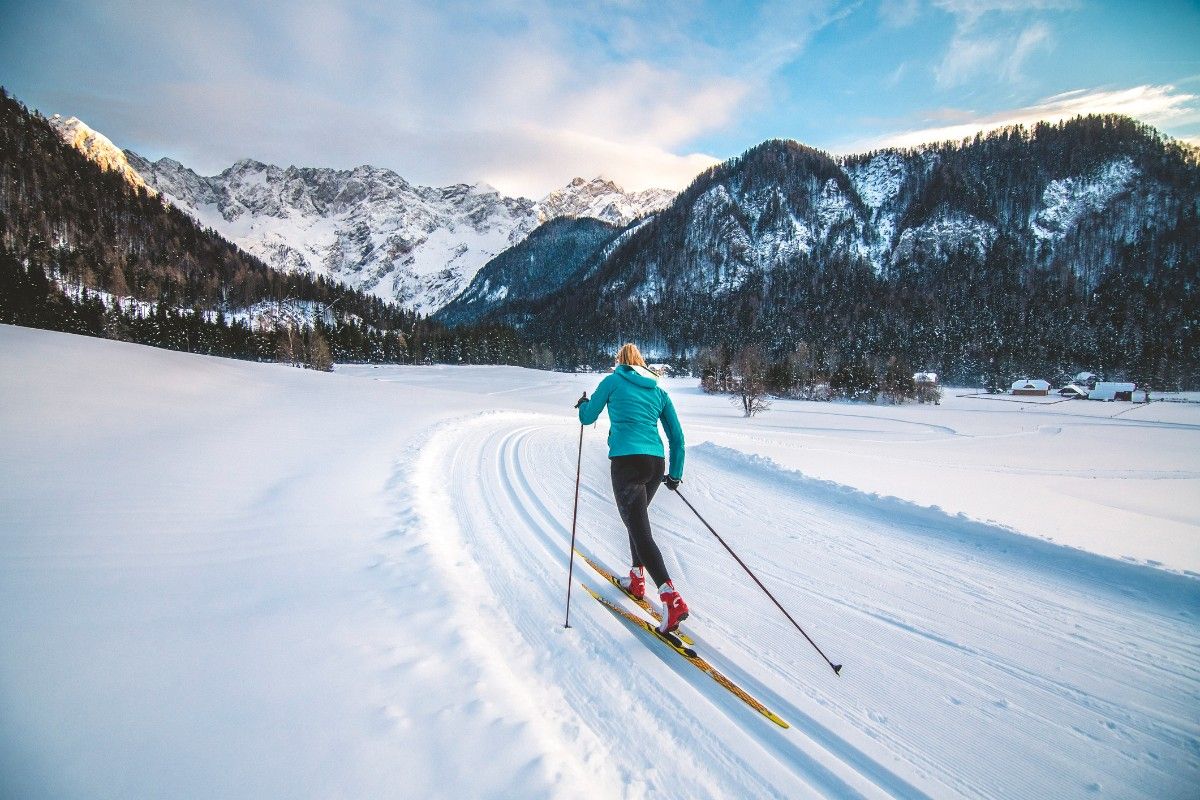 A woman cross country skiing in a green ski jacket